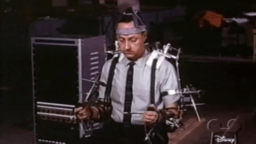 Ein Roboter aus der Attraktion „Karussell des Fortschritts“ auf der Weltausstellung von 1964 wird von Walt Disney und einem Ingenieur unter Verwendung eines Manipulationsgeräts im Waldo-Stil vorgeführt. 