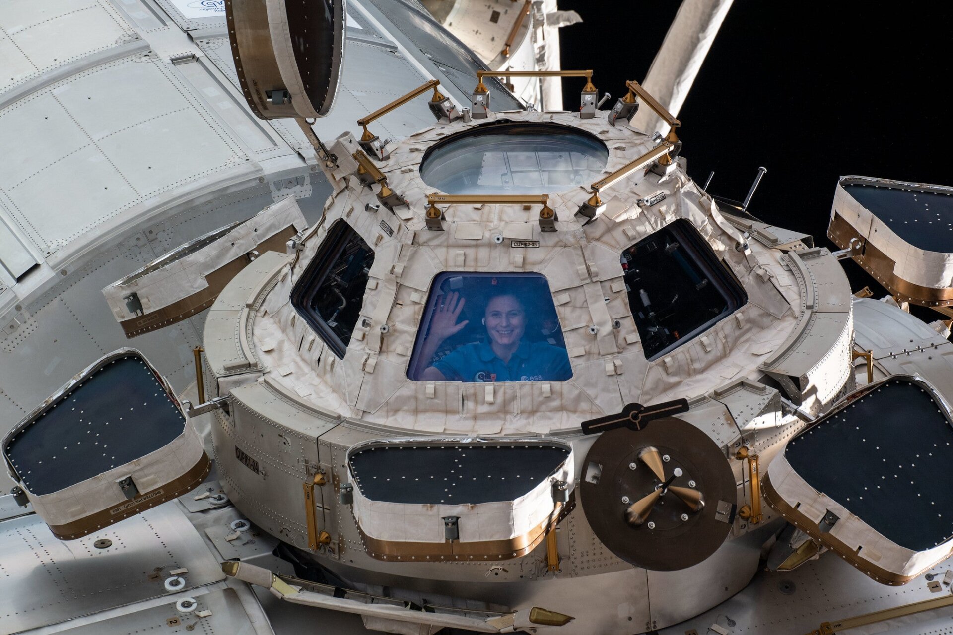 Die ESA-Astronautin Samantha Cristoforetti blickt aus einem Fenster auf die Kuppel.