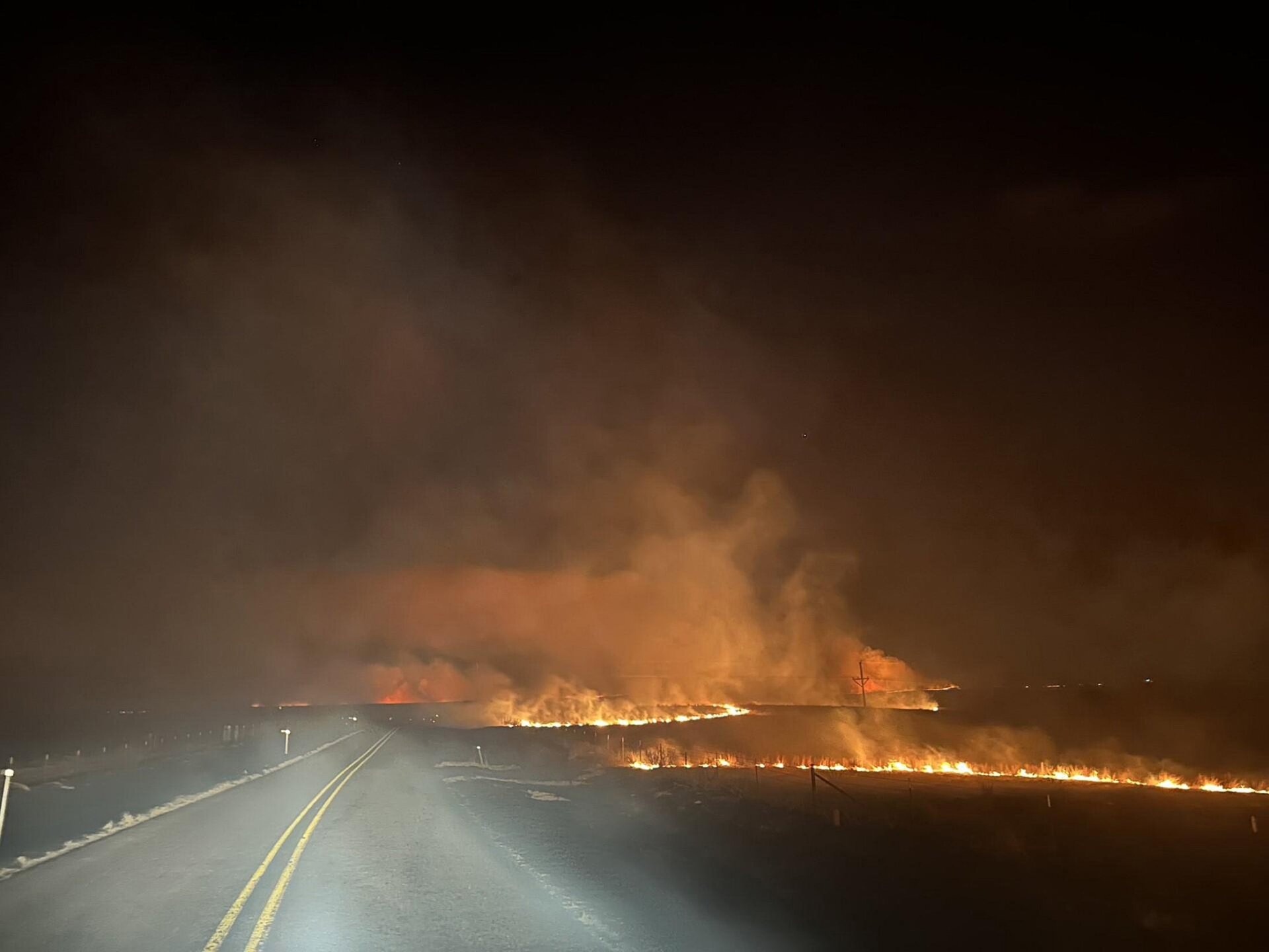   Auf diesem vom Texas A&M Forest Service zur Verfügung gestellten Handout-Foto überquert ein Feuer am Abend eine Straße im Smokehouse Creek vom  27. Februar 2024, im Texas Panhandle. 