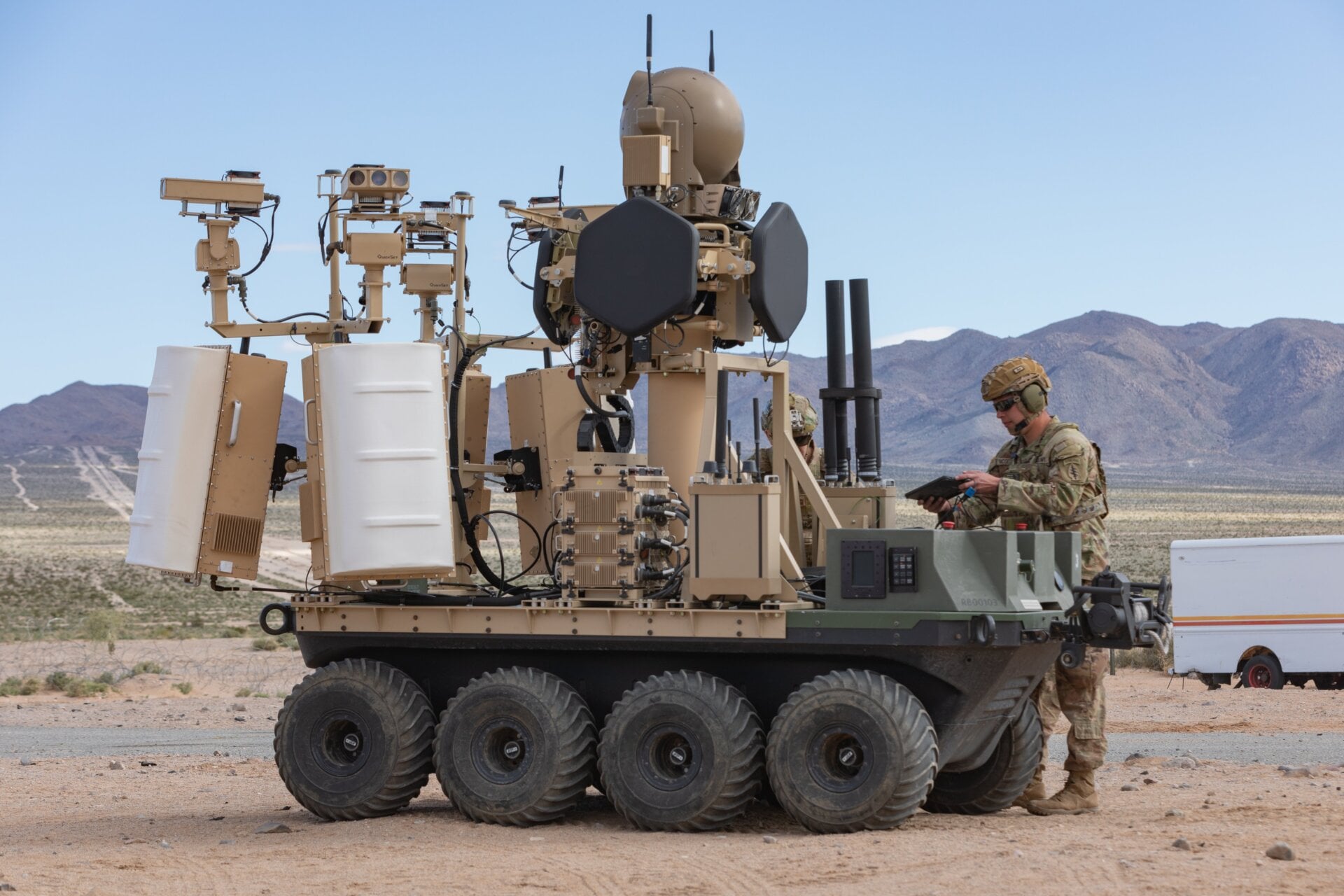 Eine unbemannte, achträdrige, vollelektrische, geländegängige Plattform der US-Armee mit einem modularen Gegen-Klein-UAS-System und einem Menschen im Gelände. Das Loop-Betriebssystem im Rahmen der Family of Counter Unmanned System oder FoCUS bietet als Teil Unterstützung für abgesessene Soldaten in einer städtischen Trainingsumgebung eines Experiments zur menschlichen Integration in Fort Irwin, Kalifornien, 18. März 2024 