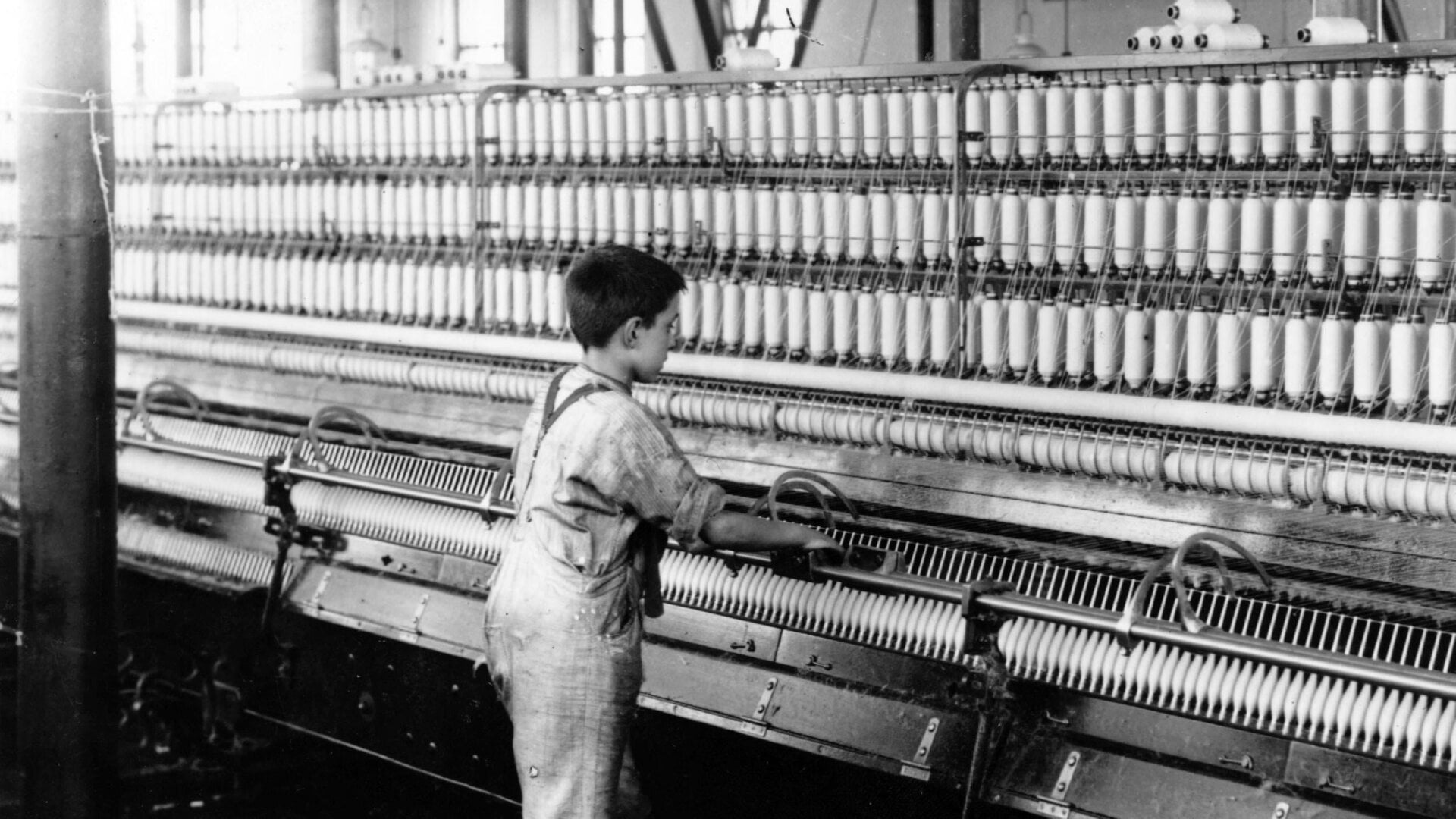 Ein kleiner Junge bediente 1909 in England eine Fadenmaschine.