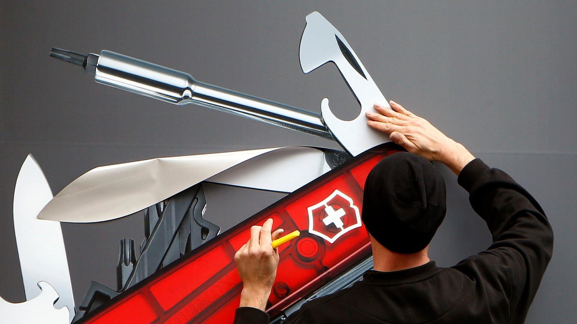 Ein Arbeiter klebt das Bild eines Schweizer Taschenmessers an das Fenster eines Victorinox-Geschäfts in Zürich, Schweiz.