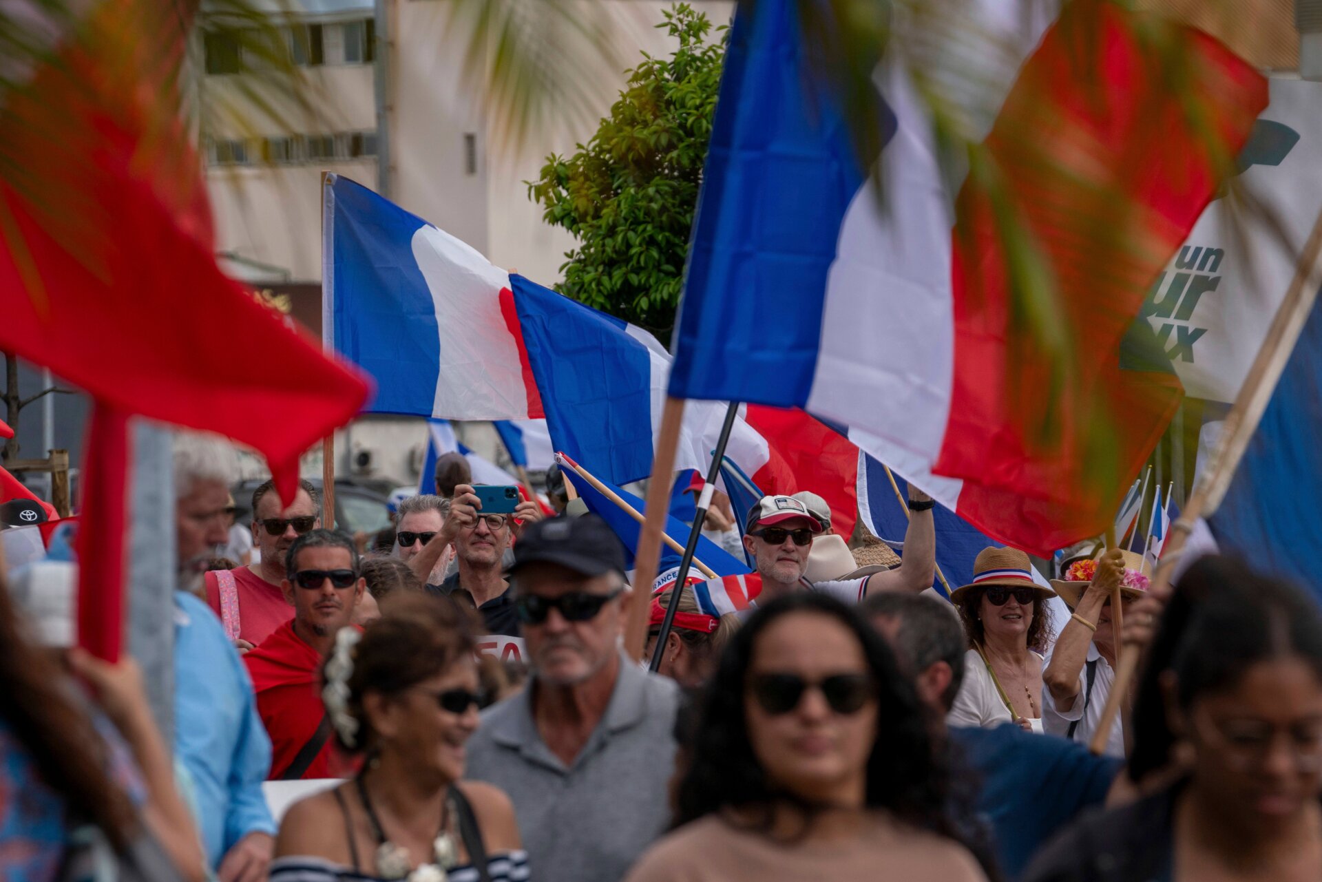 Demonstranten mehrerer loyalistischer Parteien schwenken französische Nationalflaggen, während sie am 13. April 2024 in Noumea bei einer Demonstration zur Unterstützung der Erweiterung des Wahlkreises für die bevorstehenden Provinzwahlen in Neukaledonien marschieren.