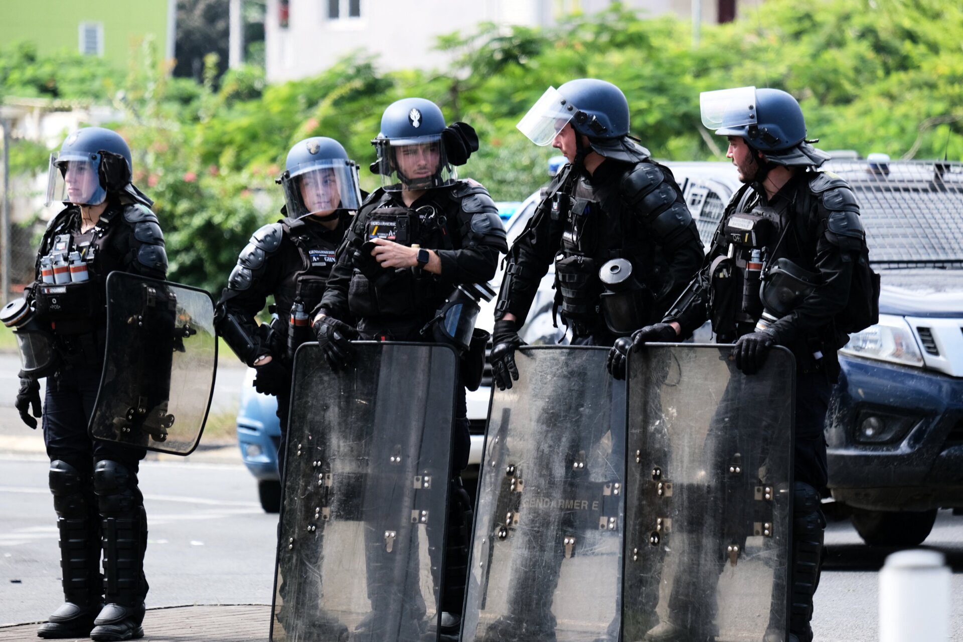 Französische Polizisten stehen am 14. Mai 2024 mit ihren Schildern am Eingang des Bezirks Vallée-du-Tir in Noumea.