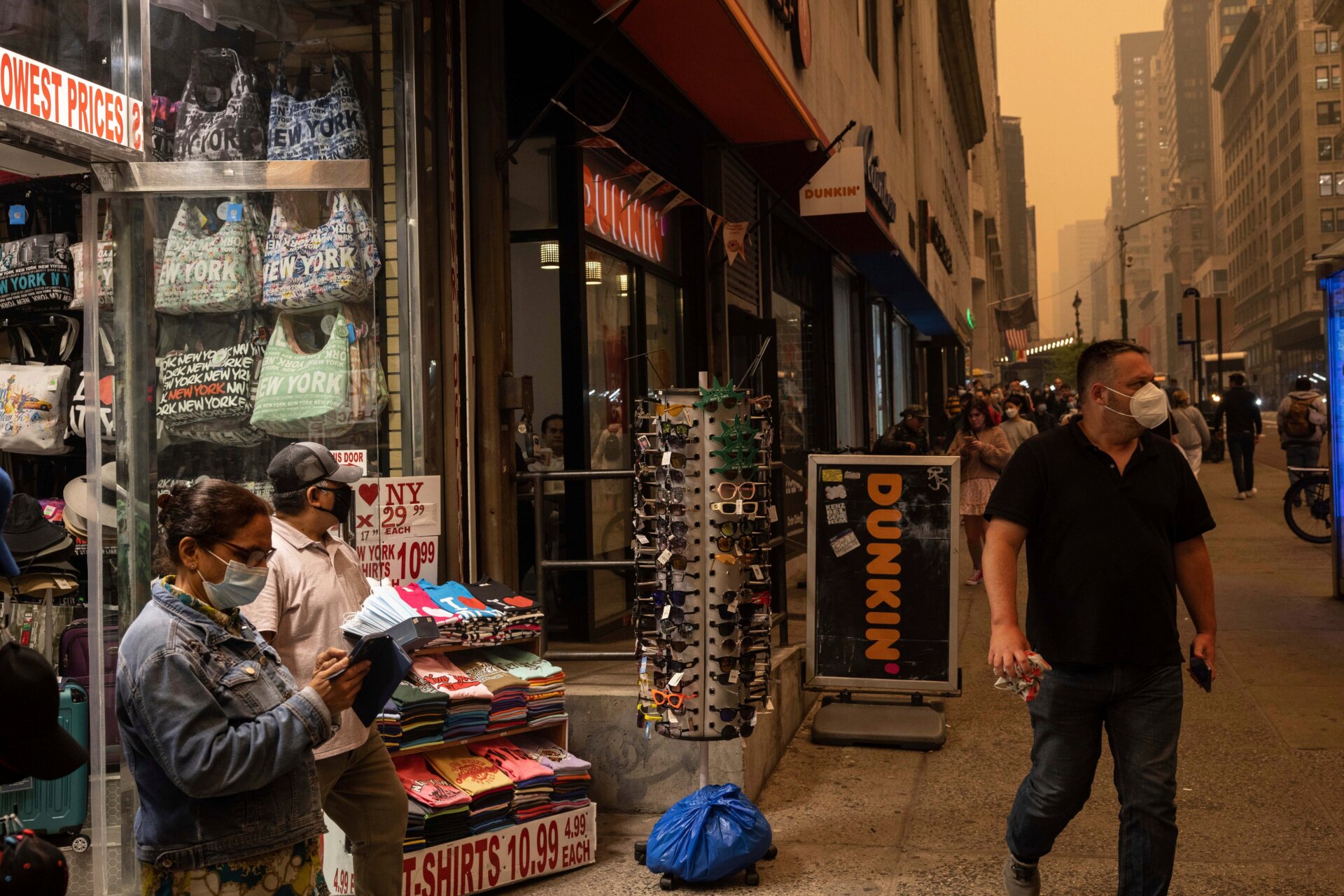 Eine Person verkauft am Mittwoch, den 7. Juni 2023, vor einem Souvenirladen in New York Gesichtsmasken, während der Rauch eines Waldbrands die Stadt einhüllt. 