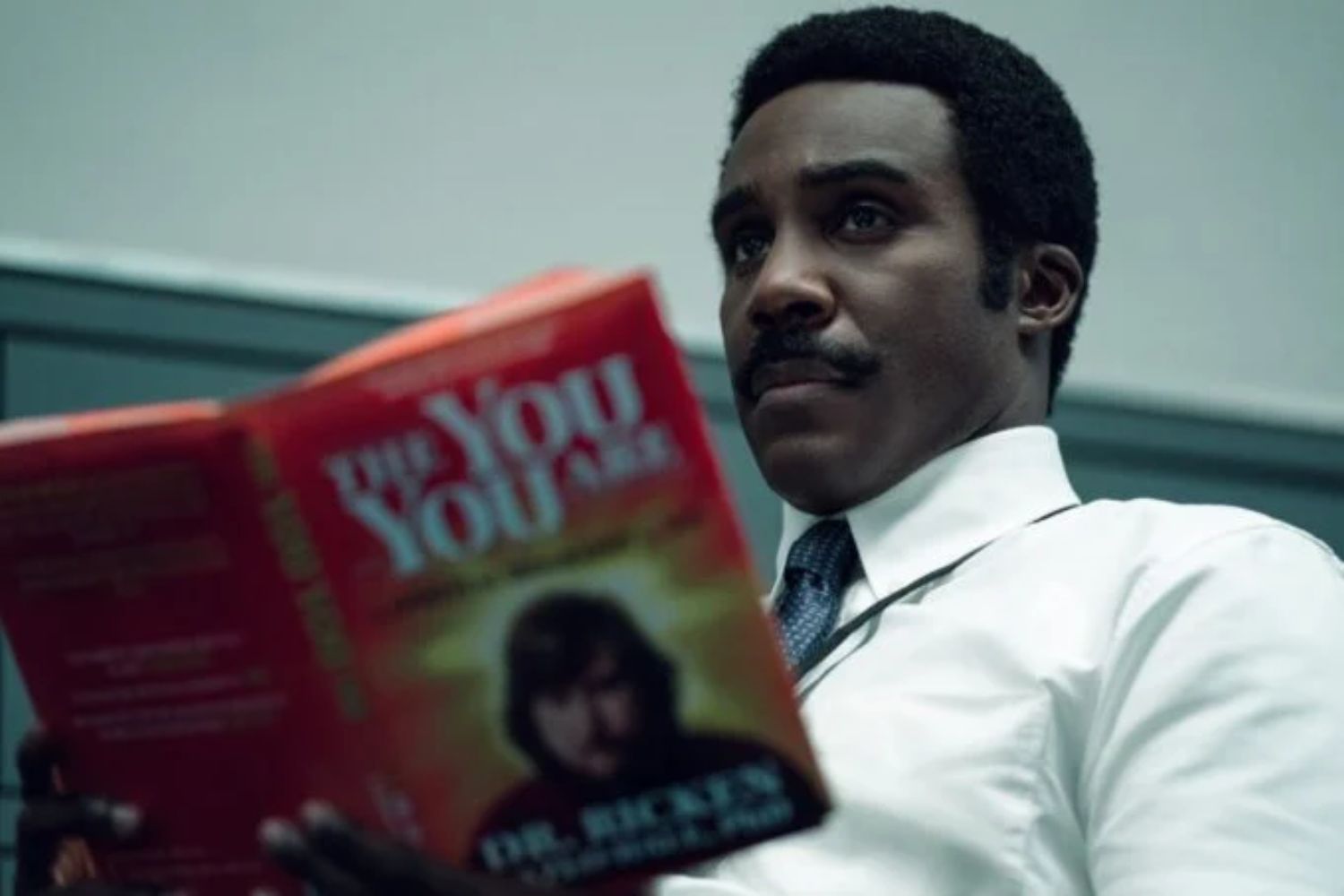 Mr. Milchick (Trammell Tillman) blättert durch Rickens Buch.