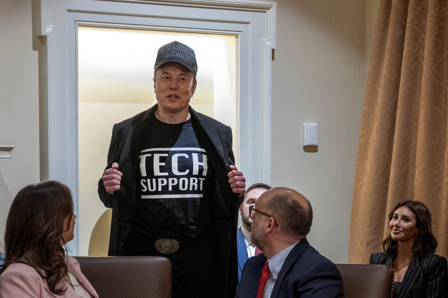 Elon Musk trägt ein Shirt mit der Aufschrift "Tech Support", während er während einer Kabinettssitzung spricht